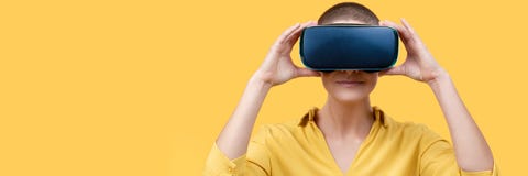 Young woman in her 30s using virtual reality goggles. Woman wearing VR headset isolated over yellow banner. VR experience. stock photography Young woman in her 30s using virtual reality goggles. Woman wearing VR headset isolated over yellow banner. VR experience. stock photography