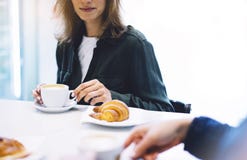 Young woman holding in female hands croissant and drink hot aroma coffee or tea in breakfast time, hipster traveler smile girl royalty free stock image Young woman holding in female hands croissant and drink hot aroma coffee or tea in breakfast time, hipster traveler smile girl royalty free stock image