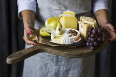 Young Woman Holding Plate Of Cheese On The Wooden Board Royalty Free Stock Photos