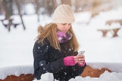 Young woman holding smartphone in the park during snowy day. royalty free stock photo Young woman holding smartphone in the park during snowy day. royalty free stock photo