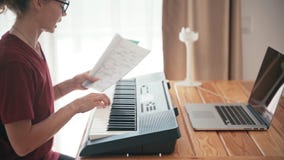 Young woman learning piano with an online course using her laptop.