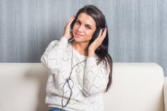 Young woman listening music with headphones in room at home on the sofa look camera stock photo Young woman listening music with headphones in room at home on the sofa look camera stock photo