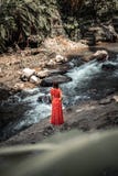 Young woman in long red dress posing on a mountain river deep in the rainforest of Bali island, Indonesia. royalty free stock photography Young woman in long red dress posing on a mountain river deep in the rainforest of Bali island, Indonesia. royalty free stock photography
