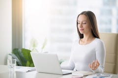Young woman practicing meditation at the office desk