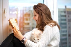 Young woman is reading a book with her cat royalty free stock photo Young woman is reading a book with her cat royalty free stock photo