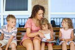Young Woman Reads Book To Two Little Girls And Boy Royalty Free Stock Image