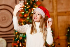 A young woman in a red Santa hat makes selfi for Christmas royalty free stock photos A young woman in a red Santa hat makes selfi for Christmas royalty free stock photos