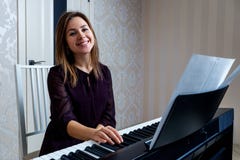 Young Woman Sitting And Playing On The Electronic Piano Royalty Free Stock Photos