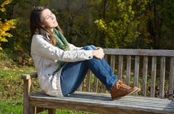 Young woman sitting on a park bench and enjoy the autumn. Young woman sitting on a park bench enjoying the autumn Stock Photography Young woman sitting on a park bench and enjoy the autumn. Young woman sitting on a park bench enjoying the autumn Stock Photography