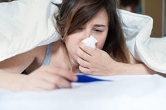 Sick woman blowing her nose lying in bed royalty free stock photo Sick woman blowing her nose lying in bed royalty free stock photo