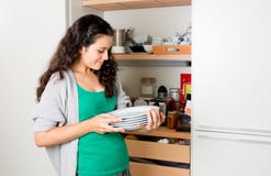 Young woman taking out dishware of the cupboard to set the table royalty free stock photo Young woman taking out dishware of the cupboard to set the table royalty free stock photo