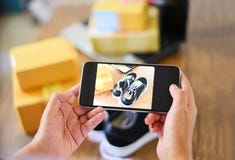 Young woman taking photo sneakers with camera smartphone for post to sell online on the internet market website / selling online stock image Young woman taking photo sneakers with camera smartphone for post to sell online on the internet market website / selling online stock image