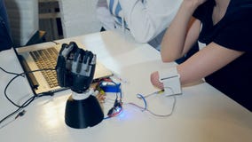 Young woman testing robotic bionic arm. Futuristic cybernetic technology in real life. stock video footage Young woman testing robotic bionic arm. Futuristic cybernetic technology in real life. stock video footage