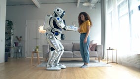 Young woman is touching a cyborg in a living room stock footage Young woman is touching a cyborg in a living room stock footage