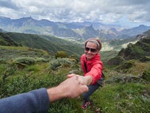 Young woman tourist in alpine zone in summer, man helping her to royalty free stock image Young woman tourist in alpine zone in summer, man helping her to royalty free stock image