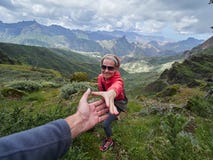 Young woman tourist in alpine zone in summer, man helping her to stock photo Young woman tourist in alpine zone in summer, man helping her to stock photo