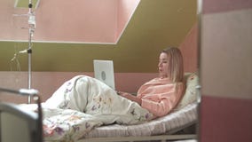 Young woman using laptop having video chat on hospital bed stock video footage Young woman using laptop having video chat on hospital bed stock video footage