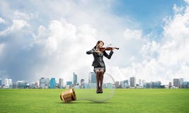 Young woman with violin sitting on big light bulb royalty free stock images Young woman with violin sitting on big light bulb royalty free stock images