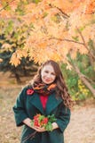 A young woman walks in the autumn Park. Brunette woman wearing a green coat. She is holding a bouquet of yellow leaves royalty free stock photo A young woman walks in the autumn Park. Brunette woman wearing a green coat. She is holding a bouquet of yellow leaves royalty free stock photo
