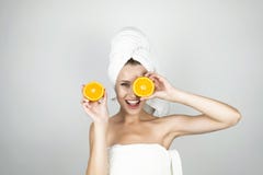 Young woman in white towel on her head holding one orange in her hand and another near her eye looking happy isolated royalty free stock images Young woman in white towel on her head holding one orange in her hand and another near her eye looking happy isolated royalty free stock images