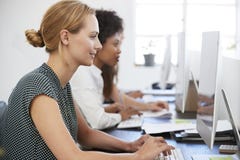 Young woman working at computer in office beside colleagues stock images Young woman working at computer in office beside colleagues stock images