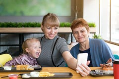 Grandmother`s daughter and granddaughter are photographed on the phone in a cafe. stock photos Grandmother`s daughter and granddaughter are photographed on the phone in a cafe. stock photos