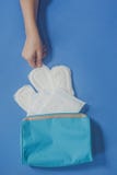 Young women taking sanitary pads inside of her cosmetic bag on blue background stock images Young women taking sanitary pads inside of her cosmetic bag on blue background stock images