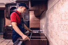 .A young worker is assembling modern wooden kitchen furniture stock images .A young worker is assembling modern wooden kitchen furniture stock images