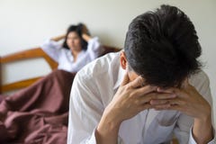 Young worried man on bed. Unhappy couple having problem in bedroom. stock photo Young worried man on bed. Unhappy couple having problem in bedroom. stock photo