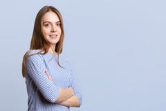 Z ukosa portret uradowana piękna młoda kobieta z długim ciemnym włosy jest ubranym ellegant pasiastą bluzkę, utrzymanie ręki krzy Zdjęcie Stock Z ukosa portret uradowana piękna młoda kobieta z długim ciemnym włosy jest ubranym ellegant pasiastą bluzkę, utrzymanie ręki krzy Zdjęcie Stock