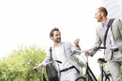 Zakenlieden die terwijl in openlucht het lopen met fietsen spreken stock foto Zakenlieden die terwijl in openlucht het lopen met fietsen spreken stock foto