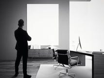 Zakenmantribunes in modern bureau met leeg wit canvas BW stock afbeeldingen Zakenmantribunes in modern bureau met leeg wit canvas BW stock afbeeldingen