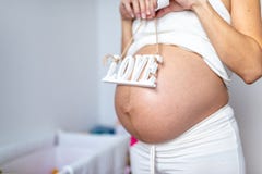 Zakończenie w górę kobiety w ciąży mienia listów miłość na jej żołądku fotografia stock Zakończenie w górę kobiety w ciąży mienia listów miłość na jej żołądku fotografia stock