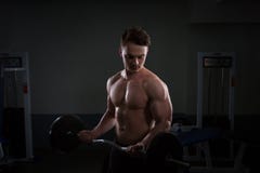 Zakończenie up młodzi mięśniowi mężczyzna udźwigu ciężary nad ciemnym tłem obraz stock Zakończenie up młodzi mięśniowi mężczyzna udźwigu ciężary nad ciemnym tłem obraz stock