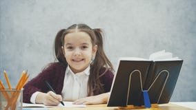 Zamyka w górę mądrze uczennicy na szarym tle Podczas ten czasu siedzi przy stołem Ostrożnie pisze pracie domowej zbiory wideo Zamyka w górę mądrze uczennicy na szarym tle Podczas ten czasu siedzi przy stołem Ostrożnie pisze pracie domowej zbiory wideo