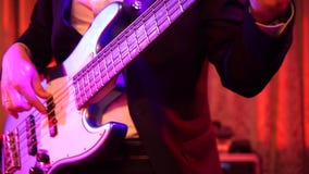 Zamyka w górę strzału mężczyźni bawić się bielu 5 sznurków basową gitarę na scenie przy nocą zbiory Zamyka w górę strzału mężczyźni bawić się bielu 5 sznurków basową gitarę na scenie przy nocą zbiory