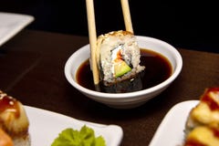 Zbliżenie mężczyzna je wyśmienicie suszi z chopsticks z jedzeniem w tle zdjęcie stock Zbliżenie mężczyzna je wyśmienicie suszi z chopsticks z jedzeniem w tle zdjęcie stock
