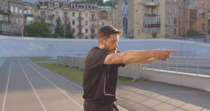 Zbliżenie portret dorosłe caucasian sporty męskie jogger rozciągania ręki na stadium w miastowym mieście outdoors zbiory wideo Zbliżenie portret dorosłe caucasian sporty męskie jogger rozciągania ręki na stadium w miastowym mieście outdoors zbiory wideo