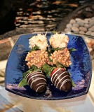 Zbliżenie strzał truskawki zamaczał w macadamia dokrętkach czekoladowych i kokosowych płatkach na błękitnego shimmer szklanym tal fotografia stock Zbliżenie strzał truskawki zamaczał w macadamia dokrętkach czekoladowych i kokosowych płatkach na błękitnego shimmer szklanym tal fotografia stock