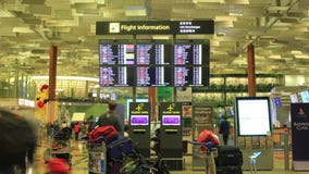 Zeit-Versehen: Internationaler Flughafen Singapurs, Changi, Besucher, die Abfahrtstafel betrachten Zeit-Versehen: Internationaler Flughafen Singapurs, Changi, Besucher, die Abfahrtstafel betrachten