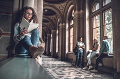 Zij houdt van lezend Mooie vrouwelijke studentenzitting op het traliewerk op de universiteit en het voorbereidingen treffen voor stock fotografie Zij houdt van lezend Mooie vrouwelijke studentenzitting op het traliewerk op de universiteit en het voorbereidingen treffen voor stock fotografie
