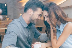 zijaanzicht van het glimlachen paarzitting bij lijst aangaande romantische datum stock foto zijaanzicht van het glimlachen paarzitting bij lijst aangaande romantische datum stock foto