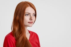 Zijdelings geschoten van mooie rode haired freckled vrouw met lang haar, denkt over iets, geconcentreerd in afstand, gekleed in r royalty-vrije stock fotografie Zijdelings geschoten van mooie rode haired freckled vrouw met lang haar, denkt over iets, geconcentreerd in afstand, gekleed in r royalty-vrije stock fotografie