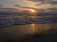 Zmierzchu widok na spokojnej piaskowatej plaży z chmurnym niebem i złotym światłem zdjęcie royalty free Zmierzchu widok na spokojnej piaskowatej plaży z chmurnym niebem i złotym światłem zdjęcie royalty free