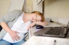 Zmęczona kobieta w ciąży śpi blisko laptopu przy jej pracującym miejscem w biurze r URLOPY MACIERZY?SCY obrazy royalty free Zmęczona kobieta w ciąży śpi blisko laptopu przy jej pracującym miejscem w biurze r URLOPY MACIERZY?SCY obrazy royalty free
