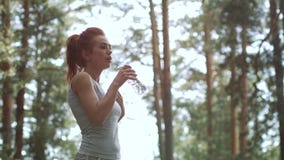 Zmęczona rudzielec dziewczyna jest wodą pitną podczas szkolenia Atleta monitoruje wodną równowagę Dziewczyna zegarki zbiory wideo Zmęczona rudzielec dziewczyna jest wodą pitną podczas szkolenia Atleta monitoruje wodną równowagę Dziewczyna zegarki zbiory wideo