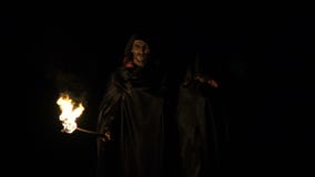 Zombie in black coats with fire in hands going in dark forest. Slowly stock footage Zombie in black coats with fire in hands going in dark forest. Slowly stock footage