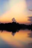 Zonsondergang over een rivier met bezinningen van bomen tegen het licht stock foto Zonsondergang over een rivier met bezinningen van bomen tegen het licht stock foto