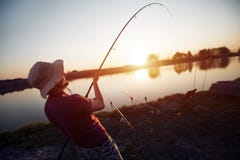 In zonsondergang vissen en mensen die terwijl het genieten van van hobby ontspannen stock afbeeldingen In zonsondergang vissen en mensen die terwijl het genieten van van hobby ontspannen stock afbeeldingen