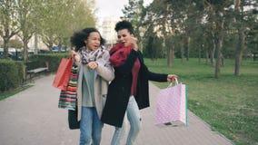 A zorra disparada de duas mulheres atrativas da raça misturada que dançam e tem o divertimento ao andar abaixo do parque com saco filme A zorra disparada de duas mulheres atrativas da raça misturada que dançam e tem o divertimento ao andar abaixo do parque com saco filme